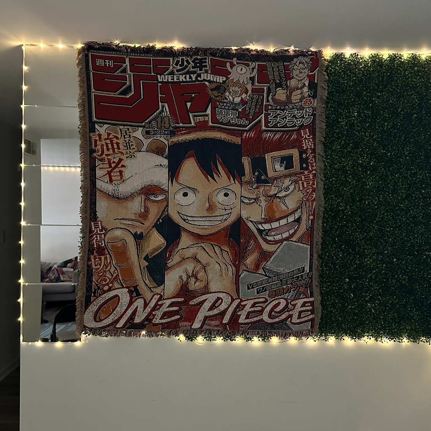 The SpicedAnime One Piece Anime Hand Woven Cozy Rug, designed like a manga cover, hangs on a wall trimmed with string lights and bordered by faux greenery—ideal as a throw, tapestry, or anime lover’s gift.